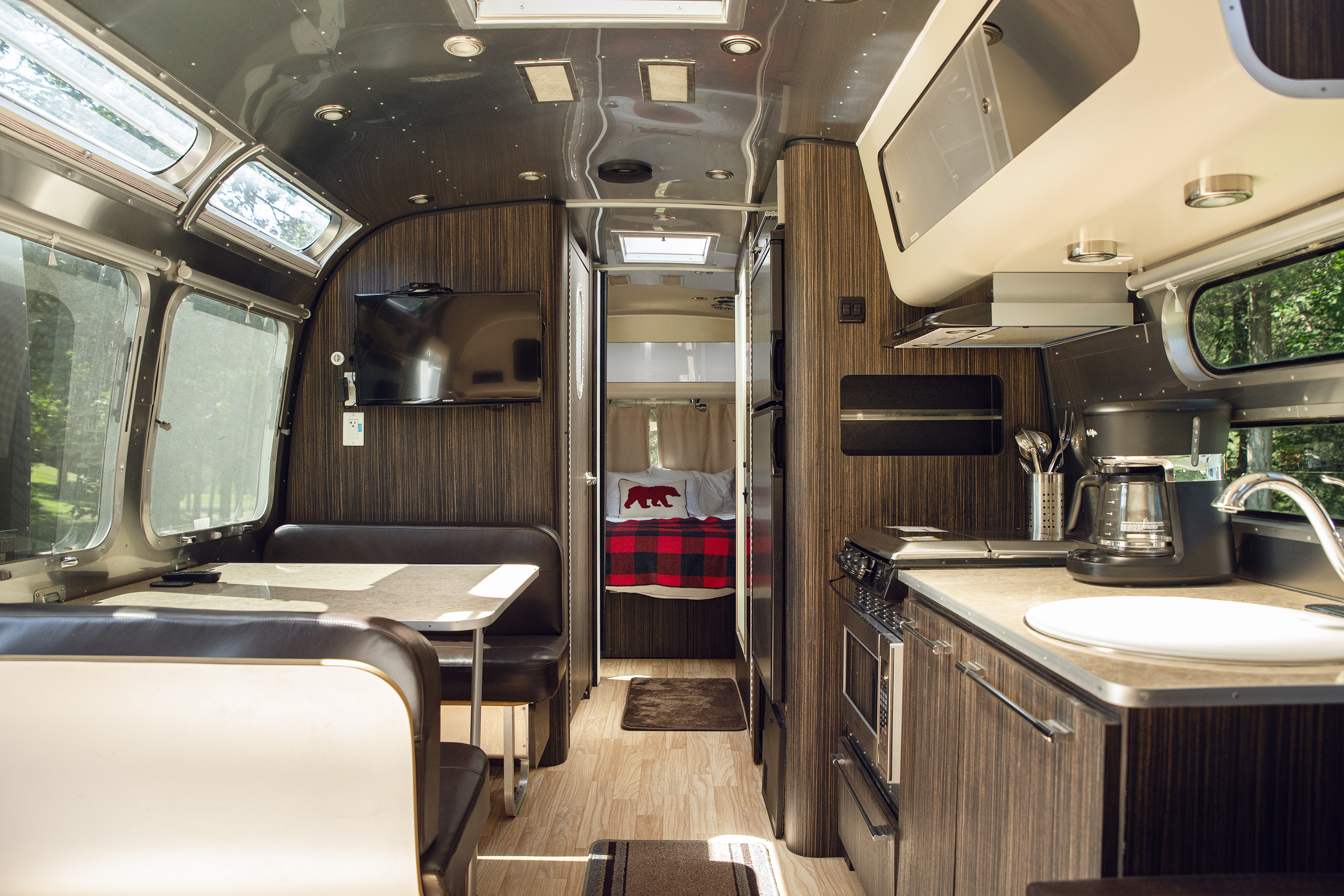 Kitchen, dining area, television, and bedroom inside the Pioneer Valley Airstream rental